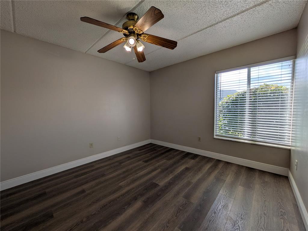 5613 Blue Shadows Court, Unit 2 Orlando, FL 32811 - Photo 13 of 26 a view of an empty room with wooden floor and a window