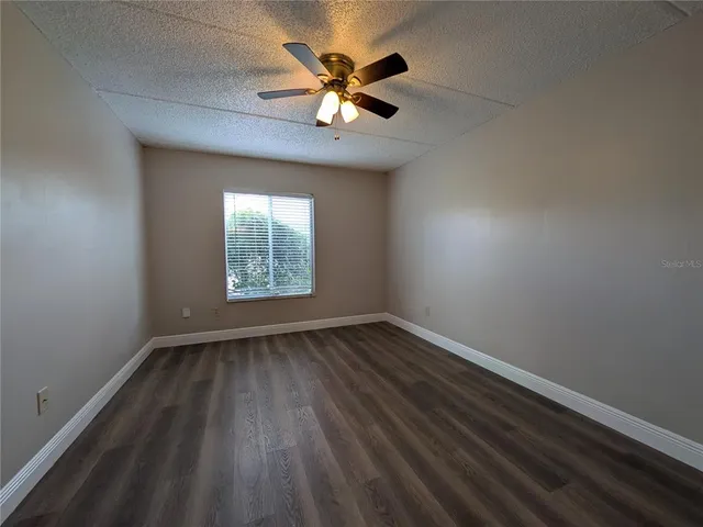 an empty room with a hardwood and ceiling fan