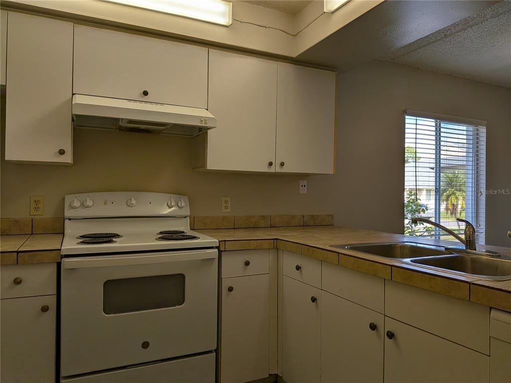 5613 Blue Shadows Court, Unit 2 Orlando, FL 32811 - Photo 9 of 26 a kitchen with cabinets appliances and a sink