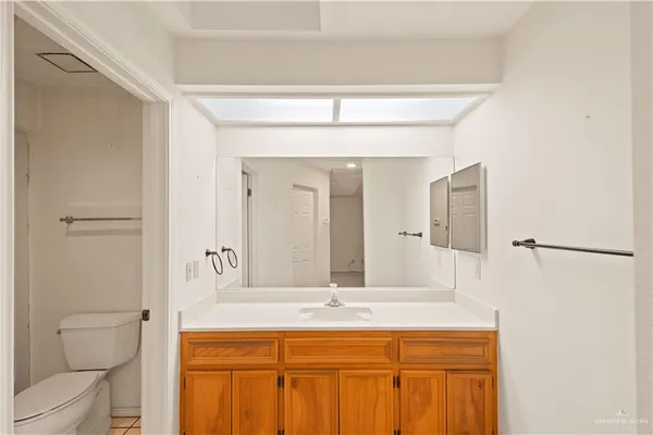 a bathroom with a granite countertop sink a toilet and a mirror