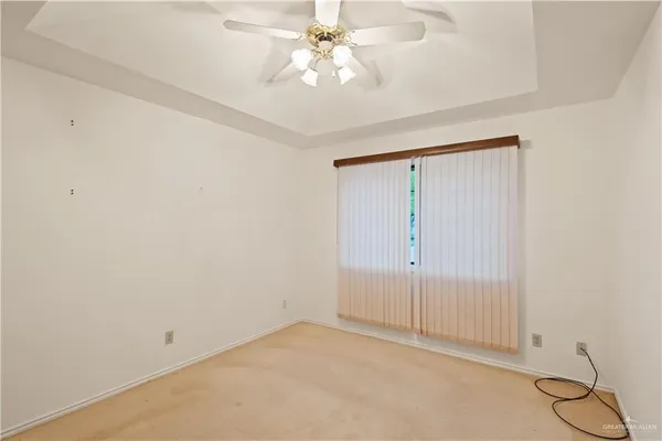 an empty room with a chandelier fan and windows