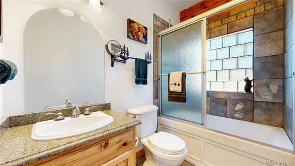 a bathroom with a granite countertop toilet sink and mirror