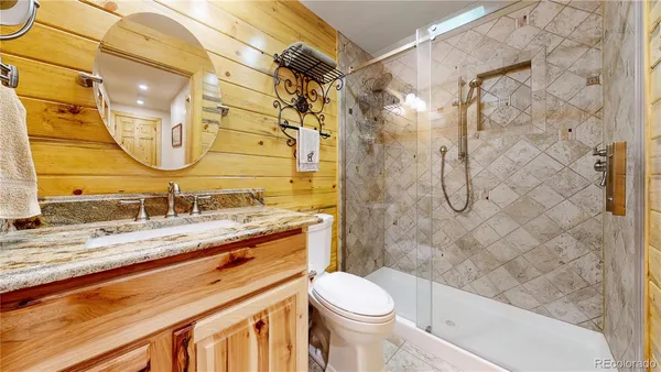 a bathroom with a granite countertop sink toilet and shower