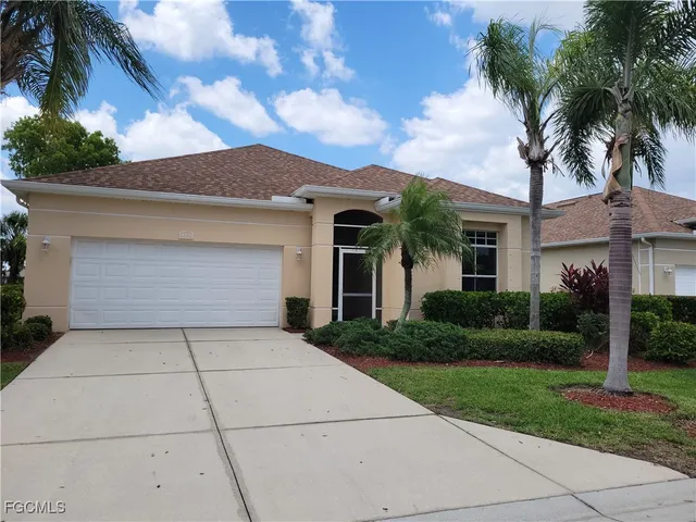 front view of house with a yard and palm trees