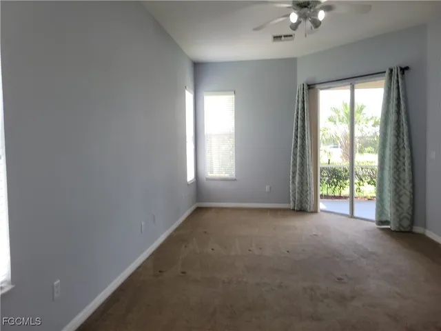 an empty room with windows and chandelier fan