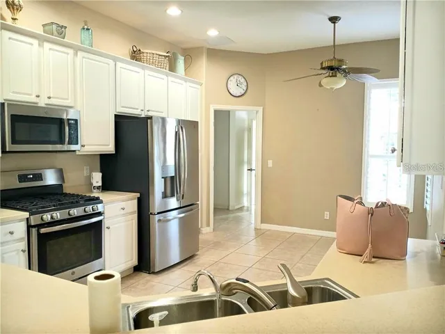 a kitchen with stainless steel appliances granite countertop a sink a stove a refrigerator and cabinets