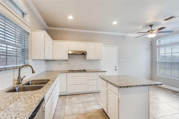 a kitchen with granite countertop a sink stainless steel appliances and white cabinets