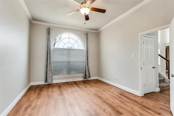 an empty room with wooden floor chandelier fan and windows