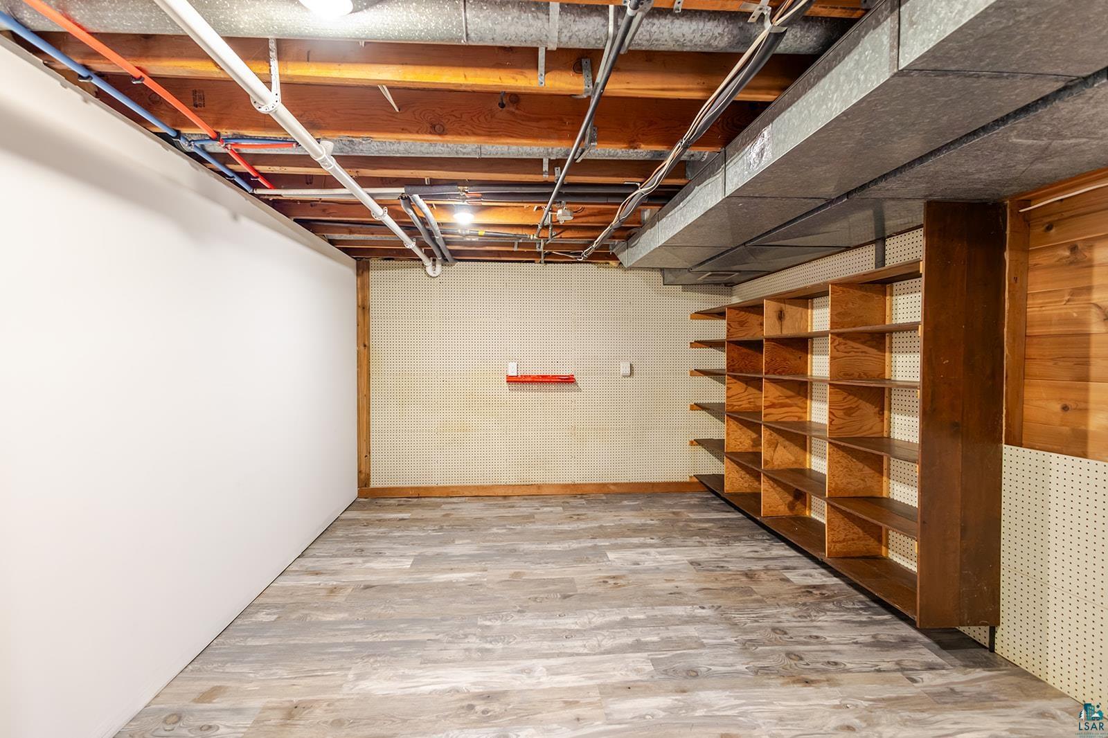 29 Ridge Road Esko, MN 55733 - Photo 29 of 41 Basement space featuring wood-finish flooring, exposed ceiling joists, and extensive built-in shelving