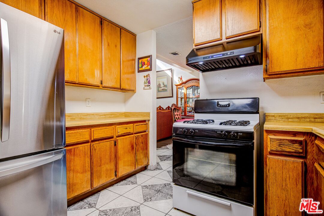 981 West Long Beach Drive Colton, CA 92324 - Photo 9 of 33 a kitchen with stainless steel appliances granite countertop a stove a washer and dryer with wooden floor