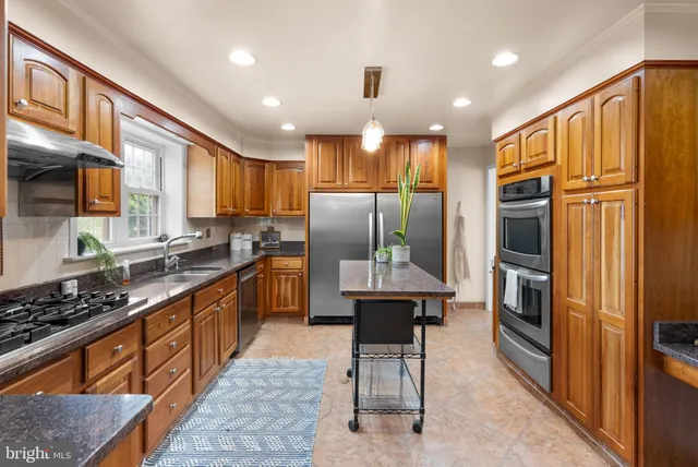 a kitchen with stainless steel appliances granite countertop a refrigerator a stove a sink a microwave and island