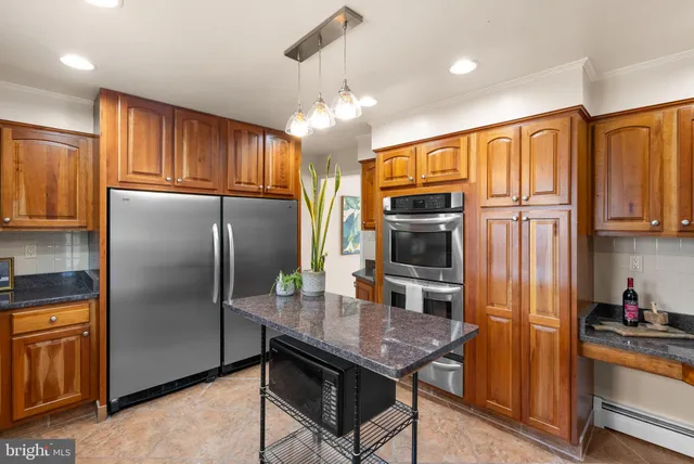 a kitchen with stainless steel appliances granite countertop a refrigerator a stove a sink dishwasher and wooden cabinets with wooden floor