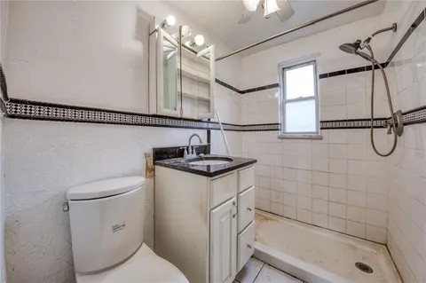 a bathroom with a granite countertop sink a toilet and shower