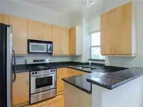 a kitchen with granite countertop a sink a stove and cabinets
