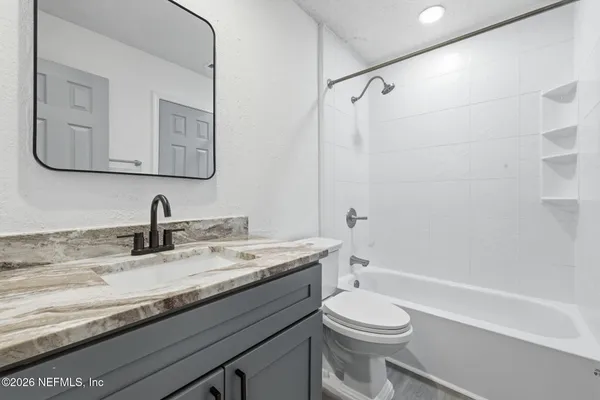 a bathroom with a granite countertop sink a mirror and next to a window