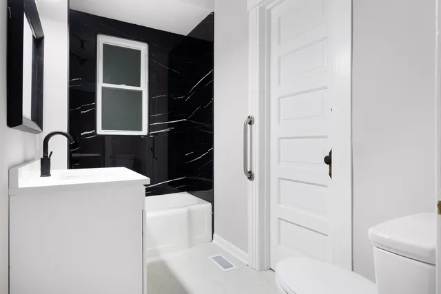 a bathroom with a sink toilet vanity and shower