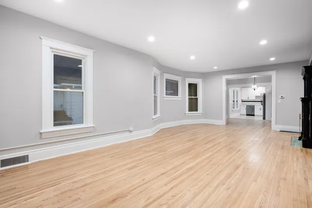 a view of empty room with wooden floor and windows
