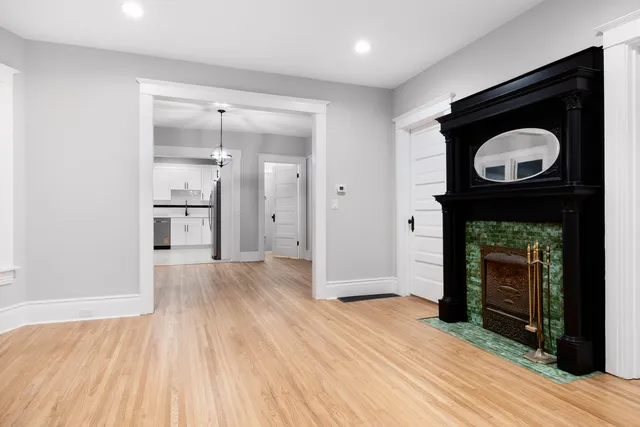a view of an empty room with wooden floor fireplace and a window