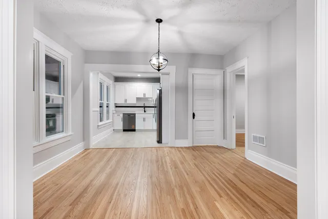 a view of a room with wooden floor kitchen view and a window