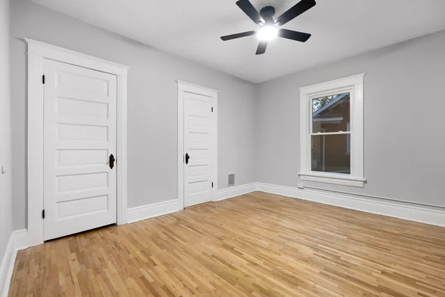a view of empty room with wooden floor and fan