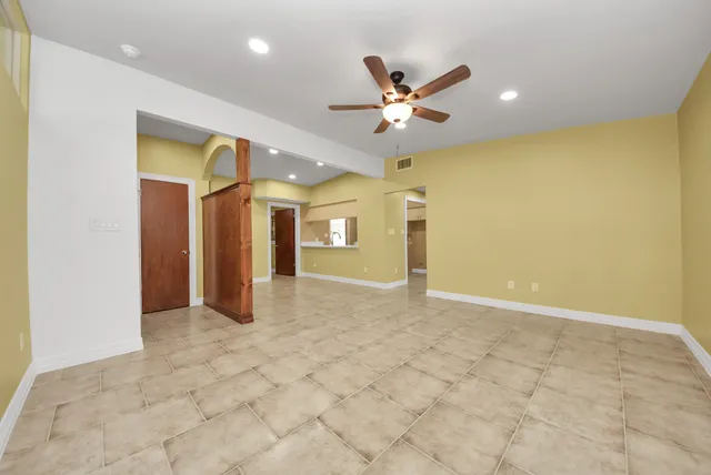 a view of a big room with wooden floor and chandelier fan