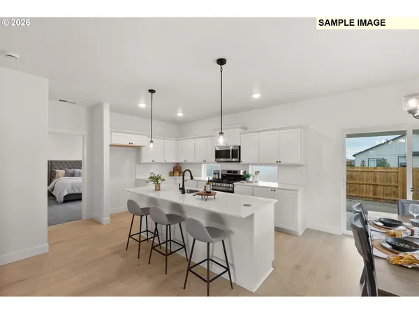 a kitchen with stainless steel appliances kitchen island a table chairs sink and cabinets