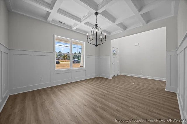 a view of an empty room and kitchen with wooden floor and a window