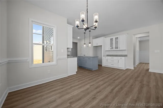 a kitchen that has a lot of cabinets in it and wooden floors