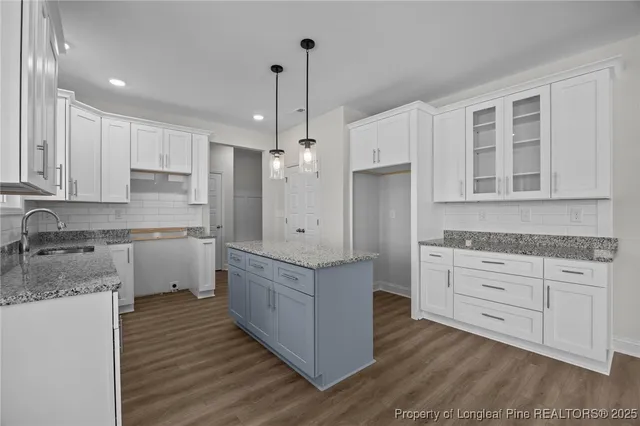 a large kitchen with granite countertop a large counter top a sink stainless steel appliances and cabinets