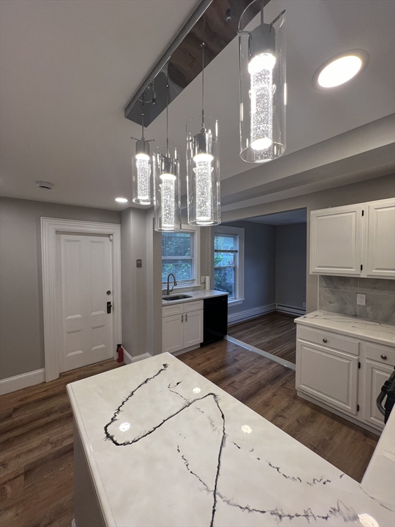 29 Ingalls Terrace, Unit 3 Swampscott, MA 01907 - Photo 3 of 13 a kitchen with kitchen island a stove a sink dishwasher and white cabinets with wooden floor