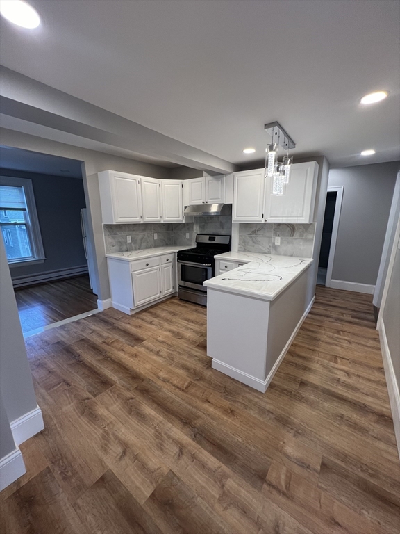 29 Ingalls Terrace, Unit 3 Swampscott, MA 01907 - Photo 4 of 13 a large kitchen with kitchen island a stove a sink dishwasher and a oven with wooden floor