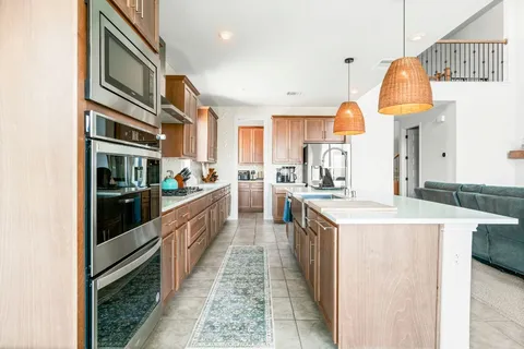 a kitchen with stainless steel appliances a stove a sink a microwave a refrigerator and cabinets