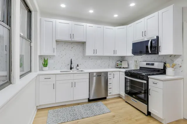 a kitchen with stainless steel appliances granite countertop a sink and cabinets with wooden floors
