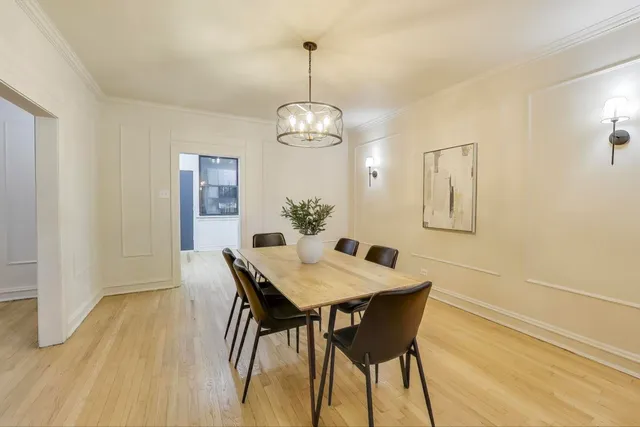 a dining room with wooden floor a chandelier a wooden table and chairs