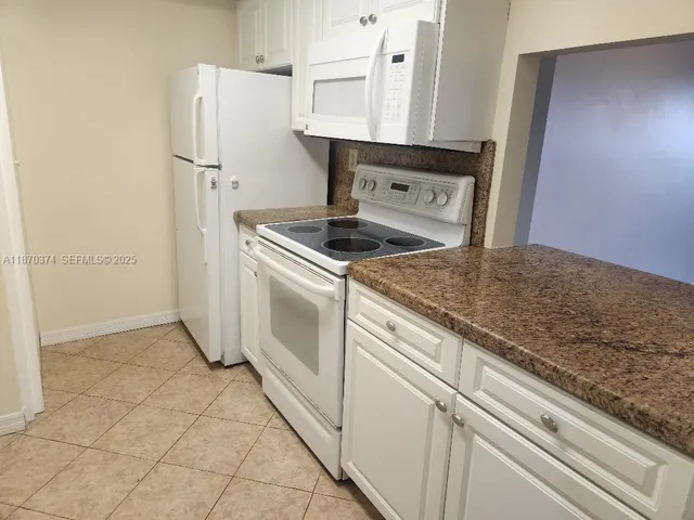 a kitchen with granite countertop a sink stove and refrigerator
