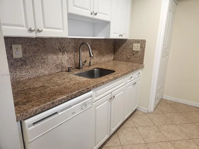 a close view of a sink and dishwasher with white cabinets