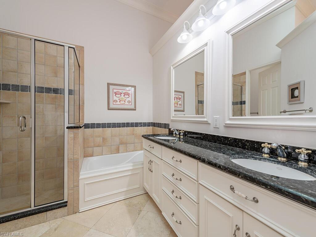165 5th Street South, Unit 3 Naples, FL 34102 - Photo 11 of 20 a bathroom with a granite countertop sink a mirror a bathtub and shower