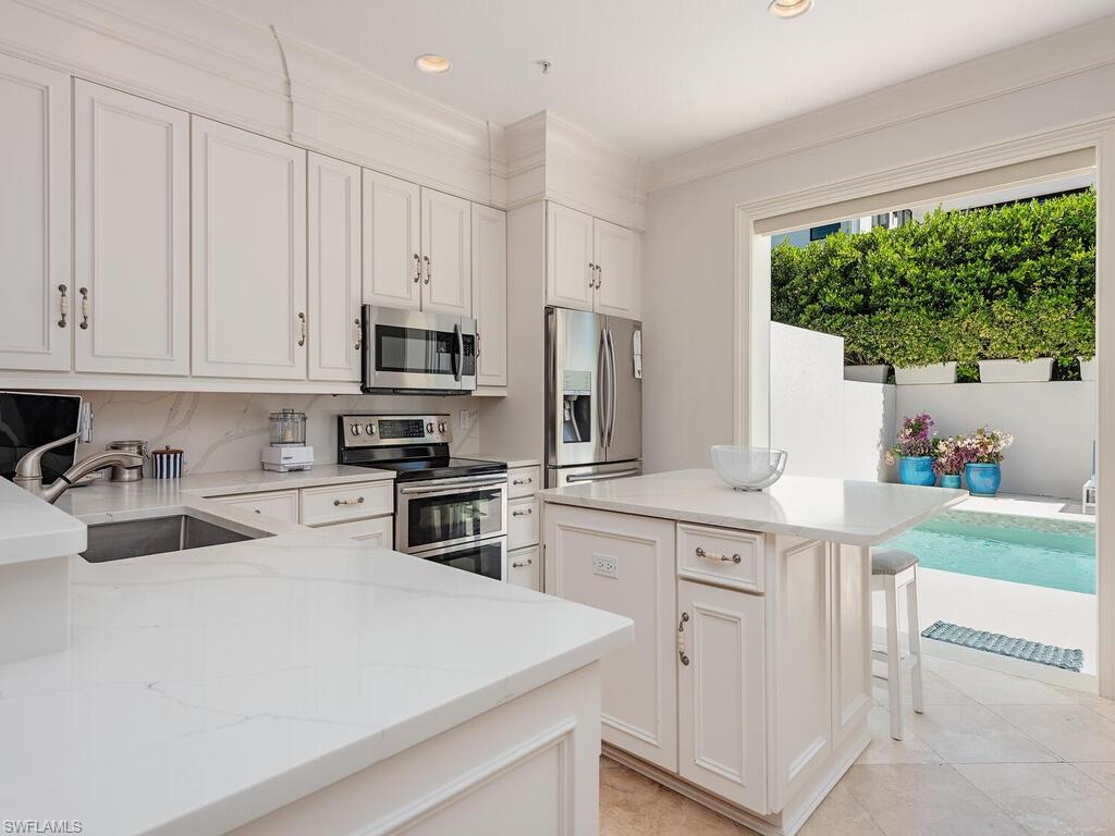 165 5th Street South, Unit 3 Naples, FL 34102 - Photo 4 of 20 a kitchen with white cabinets and stainless steel appliances