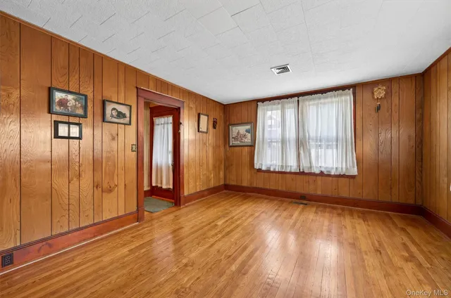 a view of an empty room with glass door and wooden floor