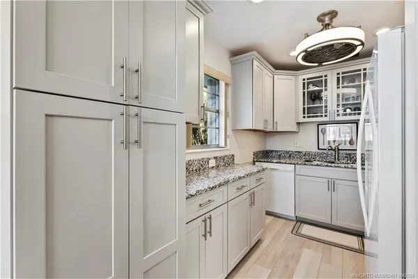 a kitchen with stainless steel appliances granite countertop a sink a stove a refrigerator and white cabinets