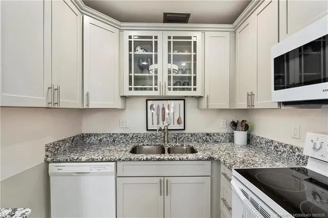 a kitchen with stainless steel appliances granite countertop white cabinets sink and granite counter top