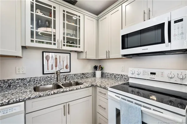 a kitchen with stainless steel appliances granite countertop white cabinets sink and stove
