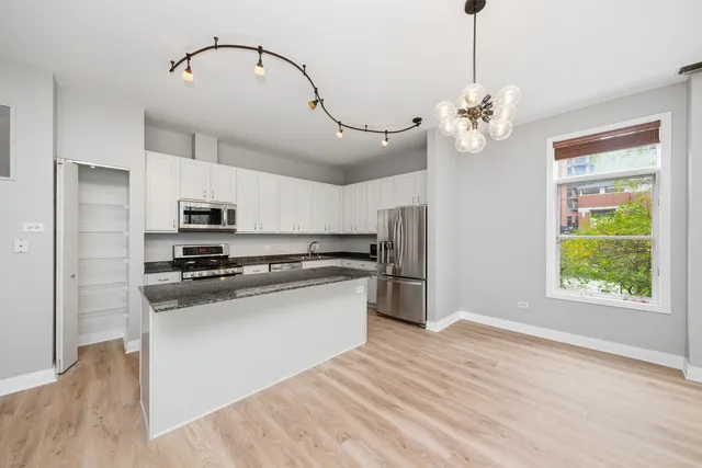 a kitchen with stainless steel appliances granite countertop a stove a refrigerator and a chandelier