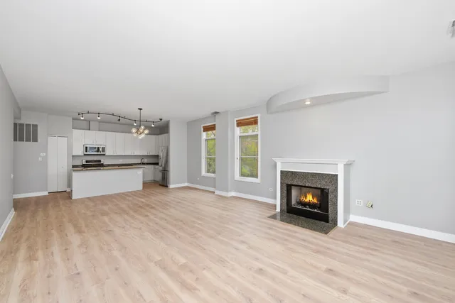 a view of empty room with kitchen and fireplace