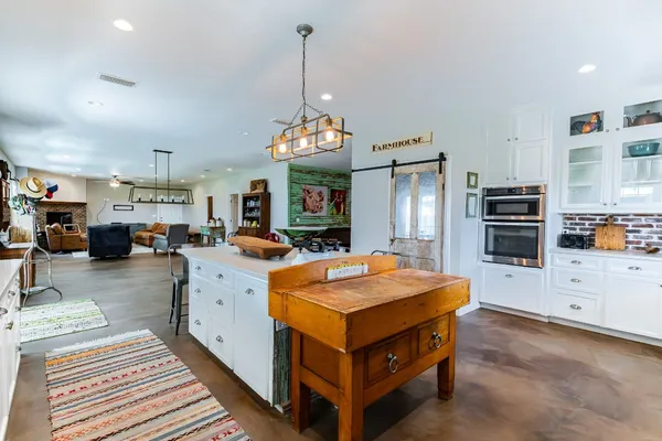 a kitchen with stainless steel appliances a dining table chairs stove refrigerator and cabinets