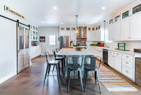 a kitchen with stainless steel appliances kitchen island granite countertop a table chairs in it and wooden floors