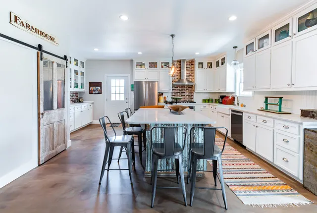 a kitchen with stainless steel appliances a dining table chairs stove refrigerator and cabinets