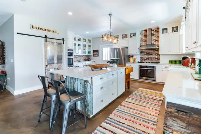 a kitchen with stainless steel appliances kitchen island granite countertop a table chairs in it and wooden floors