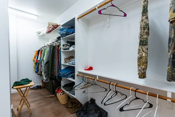 a view of walk in closet with clothes and shoes