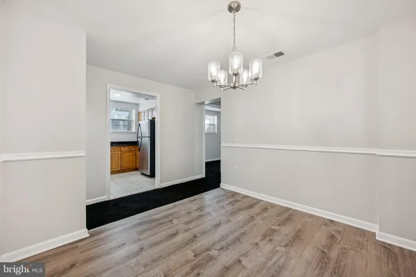 a view of empty room with wooden floor and kitchen